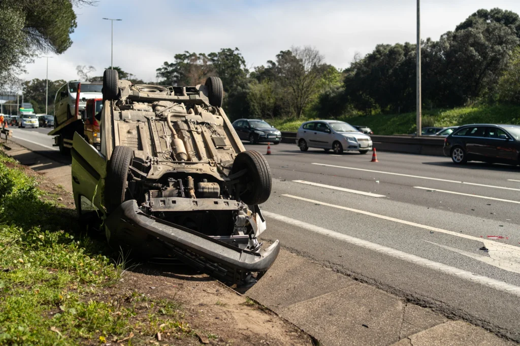 Overturned car after a road accident being recovered on the roadside with traffic nearby